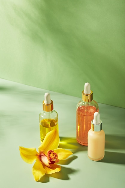 Cosmetische verzorgingsproducten in glazen flessen met orchidee bloemen serums crème gel oliën concept voor gezicht ...