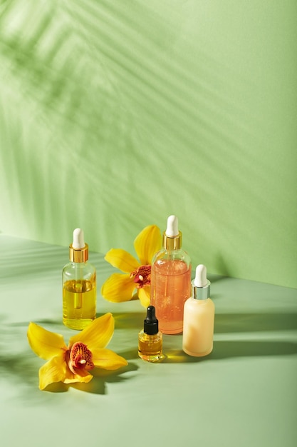 Cosmetische verzorgingsproducten in glazen flessen met orchideebloemen serums crème geloliën Concept voor gezichts- en lichaamsverzorging wellness en spa tropische ontspanning