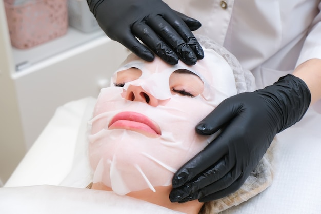 Cosmetologisch masker voor het gezicht. Jonge vrouw gezichtsverzorging.