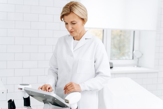 Cosmetologist adjusting settings on monitor for laser hair removal device while preparing to the patient visit. Aesthetic body treatment concept