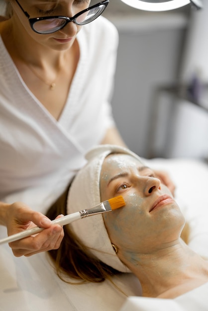 Photo cosmetologist applies beauty mask