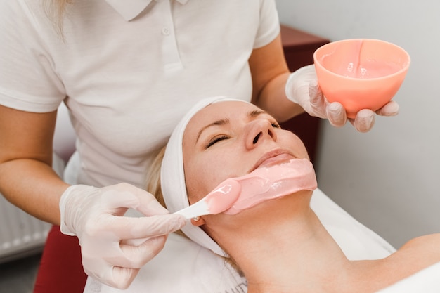 Cosmetologist applies a mask on the face of the client