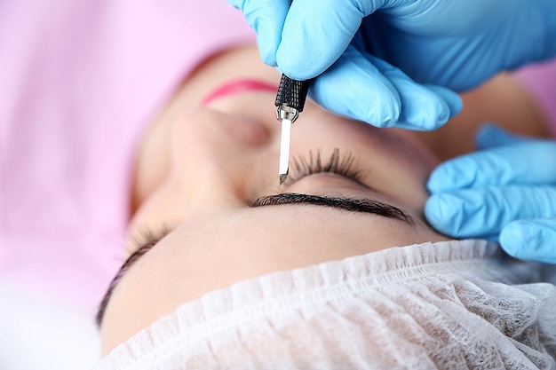 Cosmetologist applying permanent make up on eyebrows