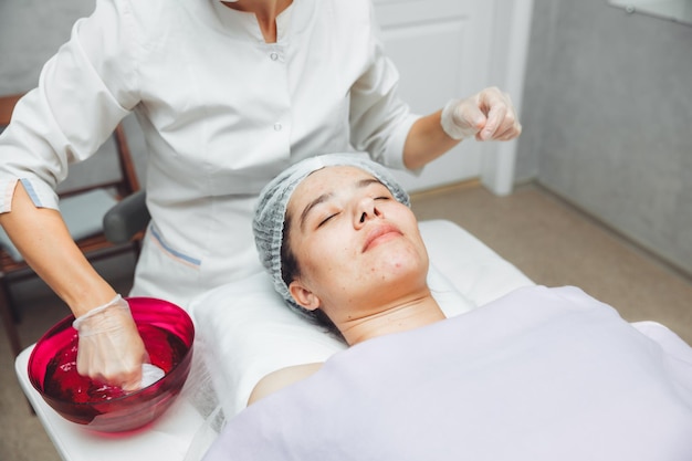 A cosmetologist cleanses the skin of a beauty salon client before the procedure and facial massage The concept of beauty and health cosmetology