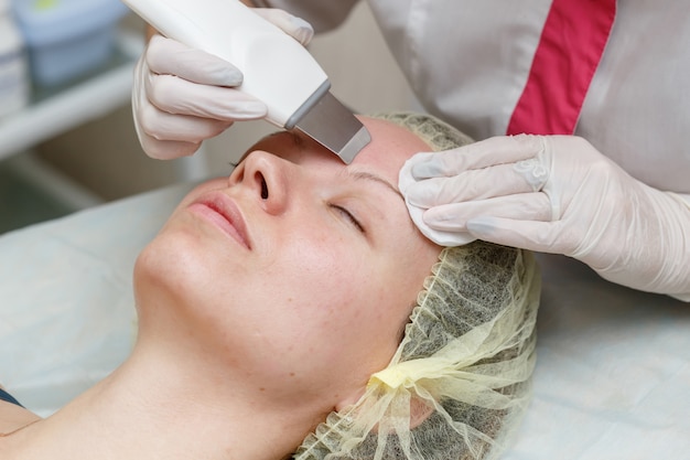 Cosmetologist die procedure doen om het gezicht met ultrasone scrubber schoon te maken