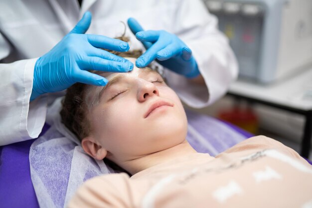 A cosmetologist doctor makes cosmetic procedures on the face of a young guy in a beauty salon