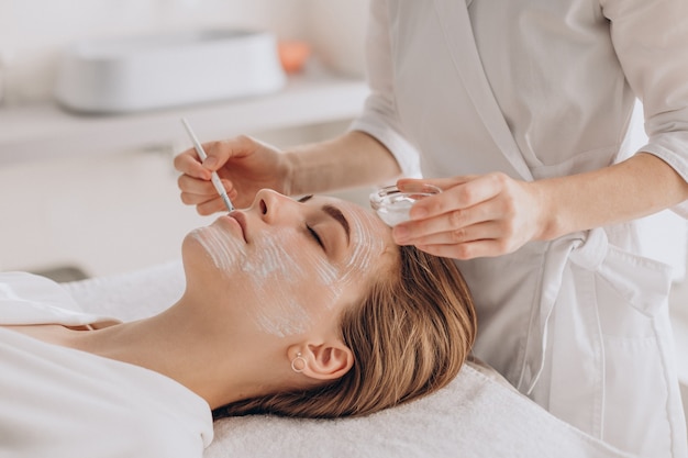 Photo cosmetologist doing face treatment and applying face mask