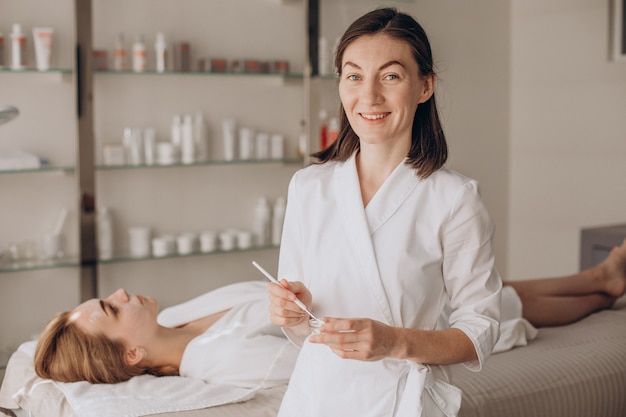 Cosmetologist doing face treatment and applying face mask