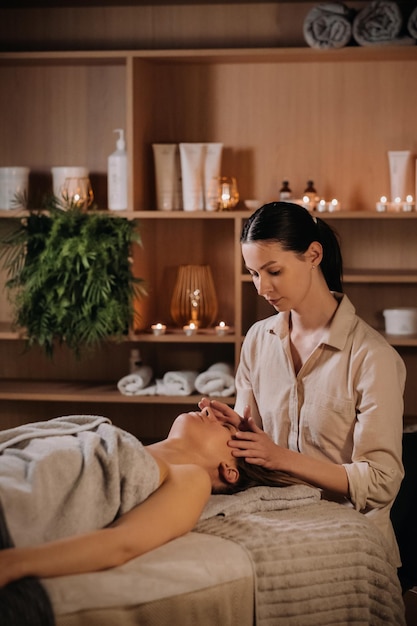 A cosmetologist girl does a facial and neck massage to a girl in the office for skin elasticity