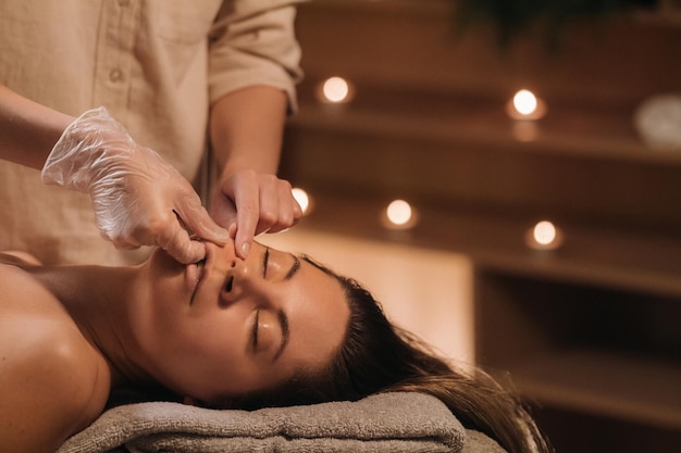 A cosmetologist girl does a facial and neck massage to a girl in the office for skin elasticity