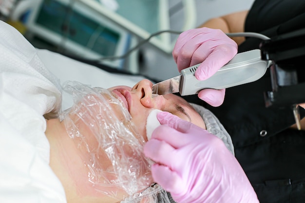 Cosmetologist girl does ultrasonic cleaning of the face