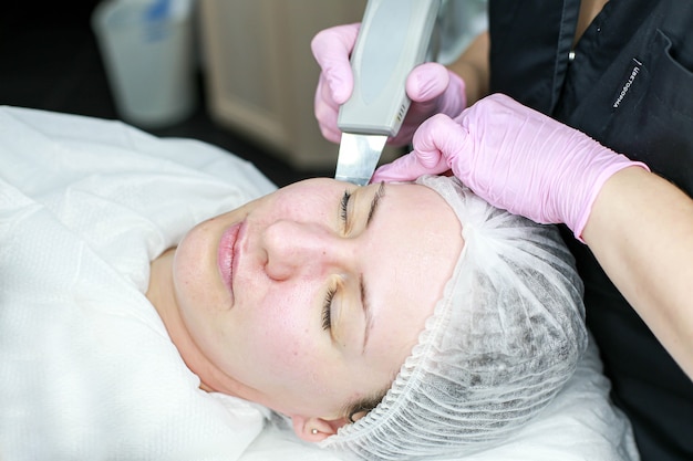 Cosmetologist girl does ultrasonic cleaning of the face