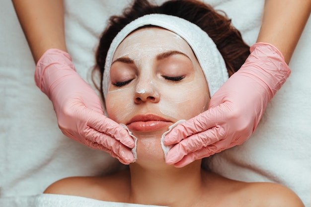 Cosmetologist giving a facial massage to a woman with sponge and gloves