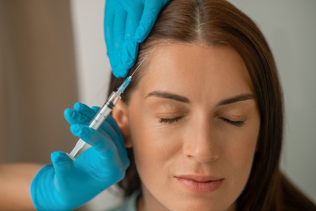 Cosmetologist injecting collagen to her clients face