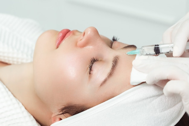 Photo the cosmetologist makes antiaging injections for the face to tighten and smooth out wrinkles on the