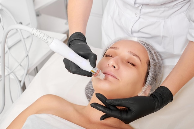 Il cosmetologo fa l'esfoliazione dell'acqua per la procedura di cura della pelle del viso della donna nel salone di bellezza
