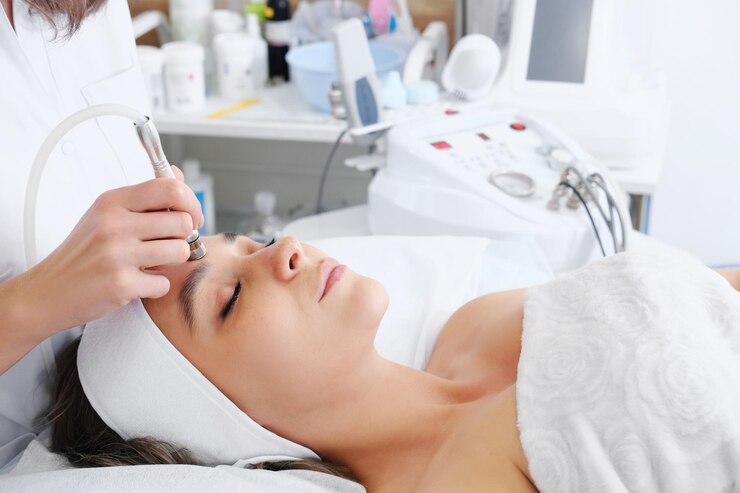 The cosmetologist makes the procedure Microdermabrasion of the skin of the face of a beautiful young woman in a beauty salon Cosmetology and professional skin care
