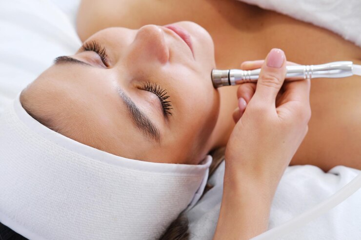 The cosmetologist makes the procedure Microdermabrasion of the skin of the face of a beautiful young woman in a beauty salon Cosmetology and professional skin care