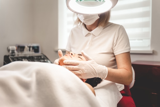 Cosmetologist massages the client's face