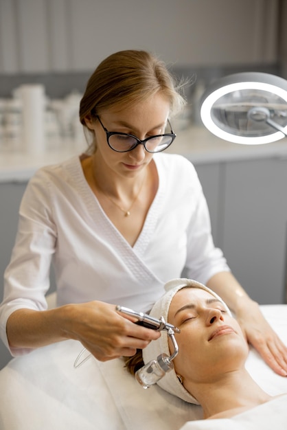 Foto il cosmetologo esegue la mesoterapia dell'ossigeno sul viso della donna
