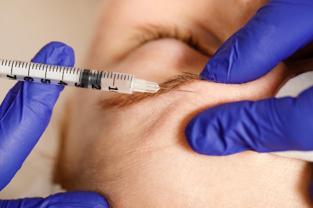 A cosmetologist performs a procedure of rejuvenating injections for the face to tighten and smooth out wrinkles on the skin of a woman's face Cosmetic skin care in a beauty salon