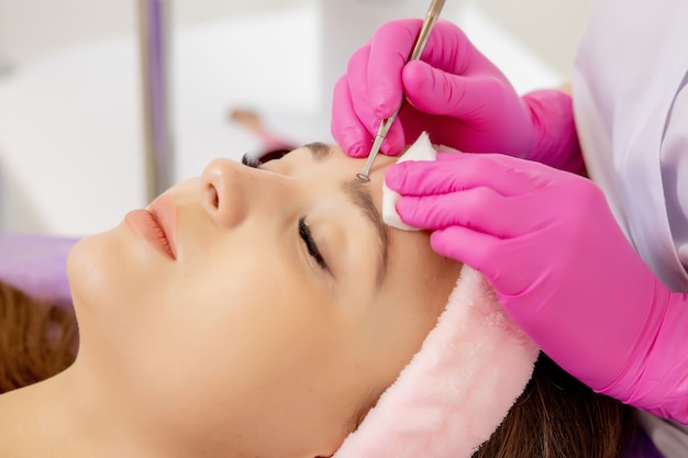 Cosmetologist at spa beauty salon doing acne treatment using mechanical instrument. Concept of medical treatment of rejuvenation and skincare.