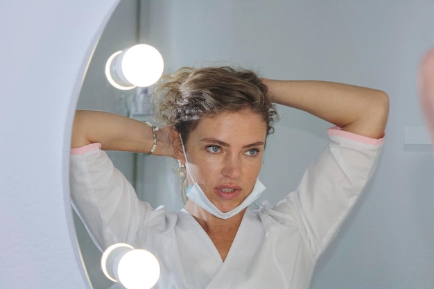 Photo a cosmetologist straightens her hair in front of a mirror in a treatment room