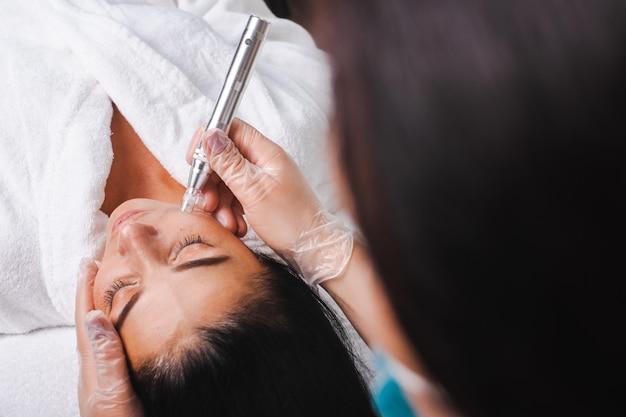 Cosmetologists hands make a water peeling procedure for the client top view spa salon closeup portra...