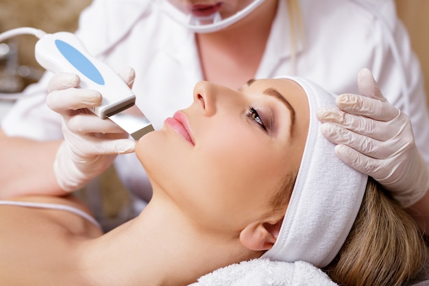 Cosmetology and beauty concept - beautiful woman receiving ultrasound cavitation facial peeling procedure