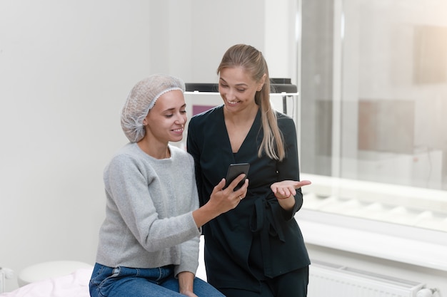 Cosmetology cabinet client sitting on couch. Beautician stands show smartphone display