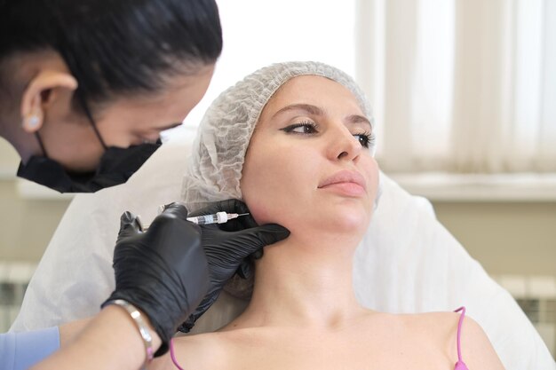 Cosmetoloog voert filler in de nasolabiale plooi van de cliënt Niet-chirurgische verjonging biedt een onmiddellijke jeugdige boost, maar brengt risico's met zich mee