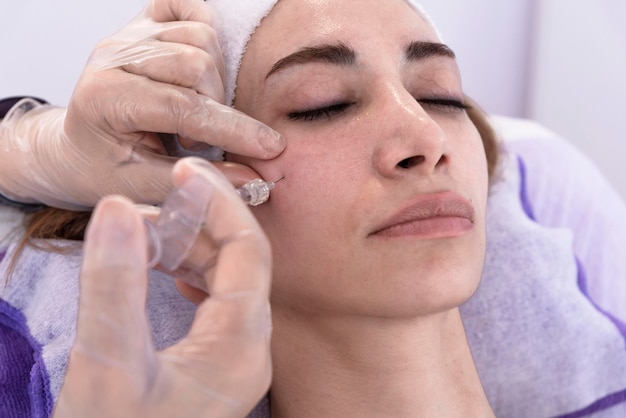 Cosmetoloog voert verjongende antirimpelvullerinjecties met hyaluronzuurvuller in het gezicht van een vrouw uit Vrouwelijke esthetische cosmetologie in een schoonheidssalon