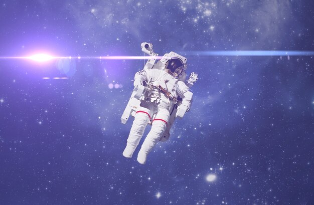 Photo a cosmonaut fly in the outer space with stars and galaxy background with a light beam. elements of this image furnished by nasa