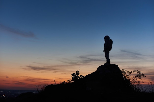 Cosmonaut standing on top of mountain during sunset