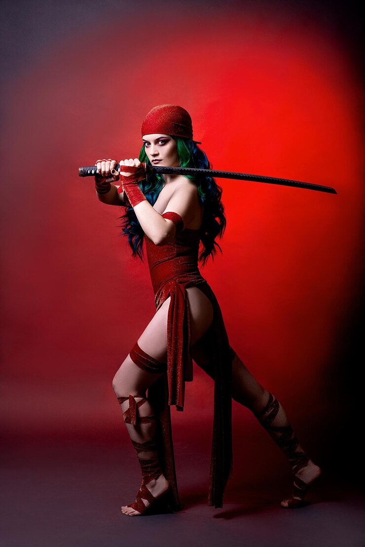 Cosplay on Elektra from the movie Daredevil Comic Con marvel girl with green hair in the studio on a red backgroundxA