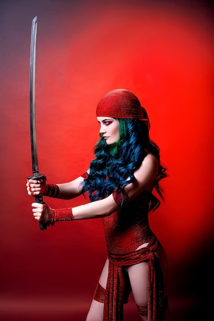 Cosplay op Elektra uit de film Daredevil Comic Con wondermeisje met groen haar in de studio op een rode achtergrondxA