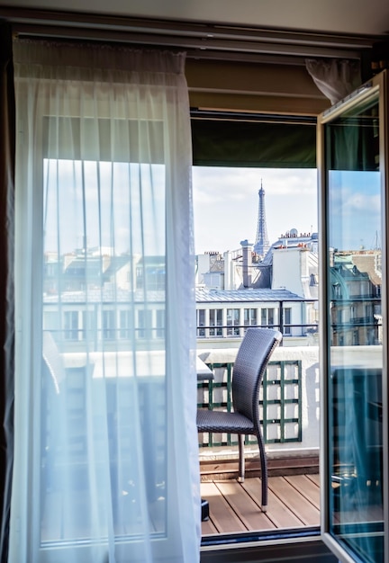 Foto accogliente camera d'albergo a parigi con balcone e bellissima vista sulla torre eiffel e sulla città