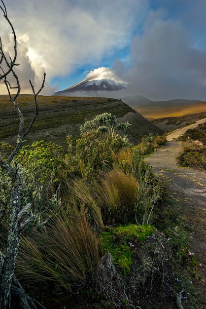 Cotopaxi volcano through a cloudy sky pierced by a ray of sunlight