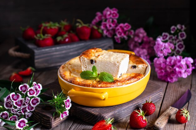 Cottage cheese bak cake braadpan met aardbeien in een ovenschaal op houten achtergrond. gezond ontbijt