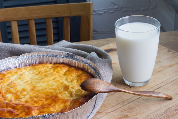 Casseruola di ricotta con bicchiere di latte sul fondo della tavola in legno. casseruola di ricotta.