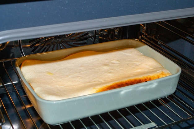 Photo cottage cheese casserole with raspberries and hazelnuts in a glass form is baked in the oven closeup