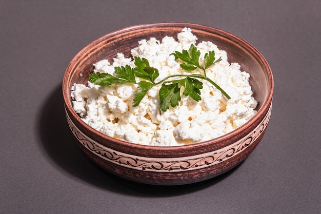 Cottage cheese in a ceramic bowl. Homemade milk product on a deep plate. Stone concrete background, copy space