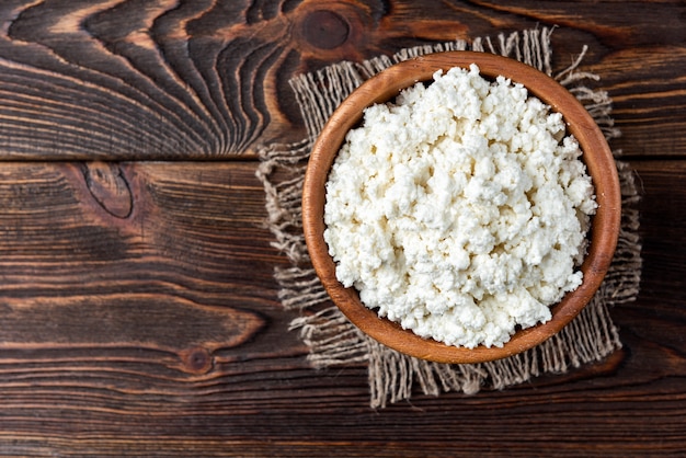 Cottage cheese on dark wooden background.