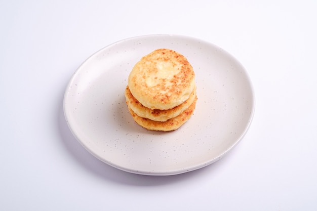Cottage cheese fritters. Dessert breakfast in plate on white, angle view