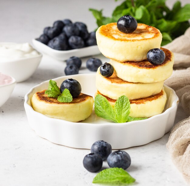 Cottage cheese fritters (syrniki) with fresh blueberries, mint and sauce. 