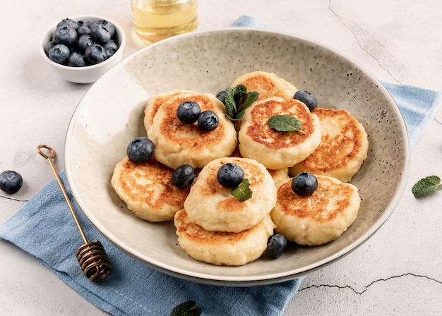 Cottage cheese fritters with blueberries on ceramic plate on concrete background Healthy calcium breakfast lunch or snack Traditional russian food Close up