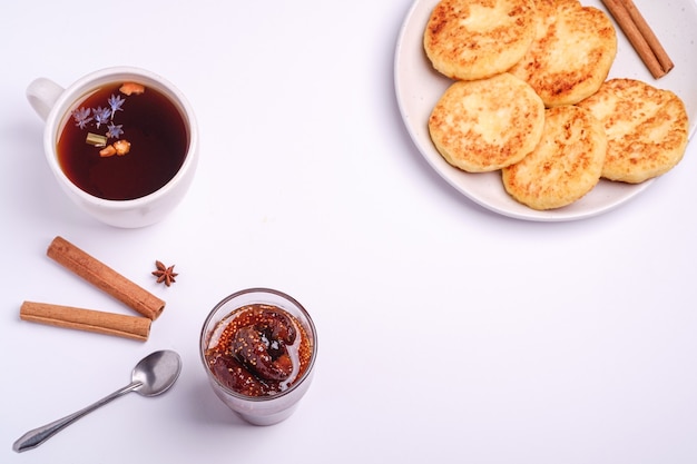 Cottage cheese fritters with fig jam and hot black aromatic tea, winter breakfast mood with anise and cinnamon