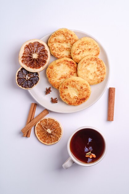 Cottage cheese fritters with hot black aromatic tea, Christmas breakfast with anise and cinnamon