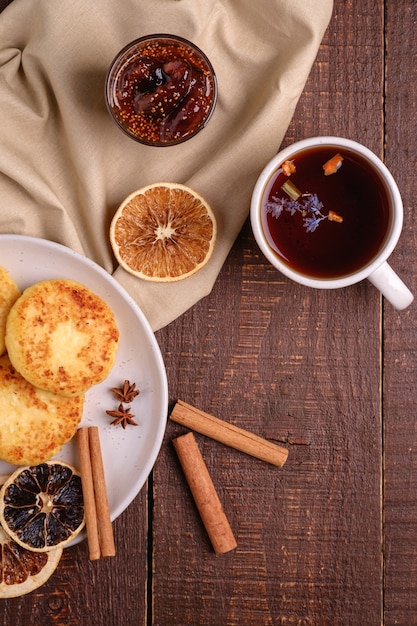 Творожные оладьи с горячим черным ароматным чаем с инжирным вареньем, настроение зимнего завтрака с анисом, корицей и сушеными цитрусовыми