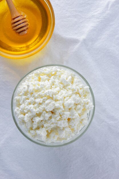 Cottage cheese and honey on white background fresh cottage cheese in glass bowl on white cloth